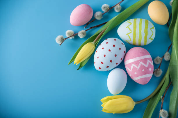 istock Colorful Easter eggs with yellow Tulip hand painted on a blue background. Holiday spring card 929548952