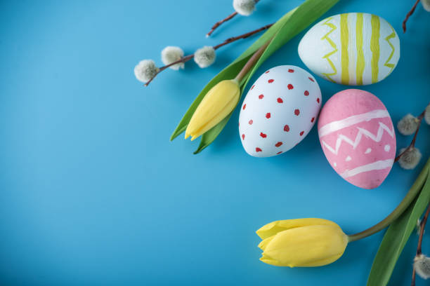 istock Colorful Easter eggs with yellow Tulip hand painted on a blue background. Holiday spring card 929548966