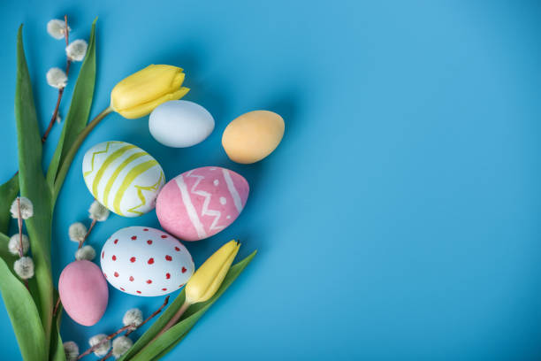 istock Colorful Easter eggs with yellow Tulip hand painted on a blue background. Holiday spring card 929549026