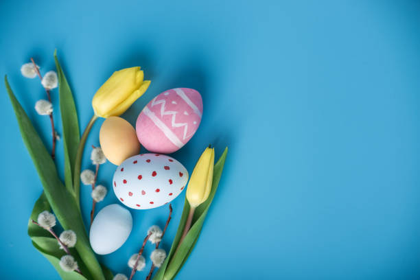 istock Colorful Easter eggs with yellow Tulip hand painted on a blue background. Holiday spring card 929549038