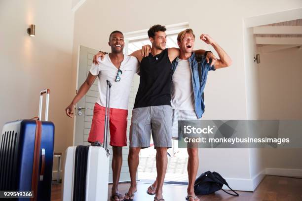 Group Of Male Friends Arriving At Summer Vacation Rental Stock Photo - Download Image Now