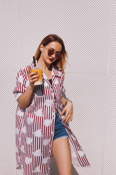 istock beautiful young woman in striped red shirt with mango shake in plastic cup 929552406