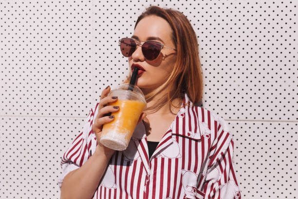 istock beautiful young woman drinking cocktail from plastic cup 929555352