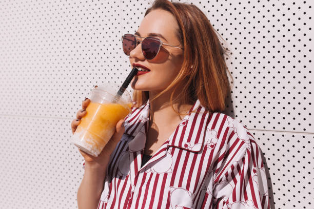 istock smiling young woman drinking cocktail from plastic cup 929555510
