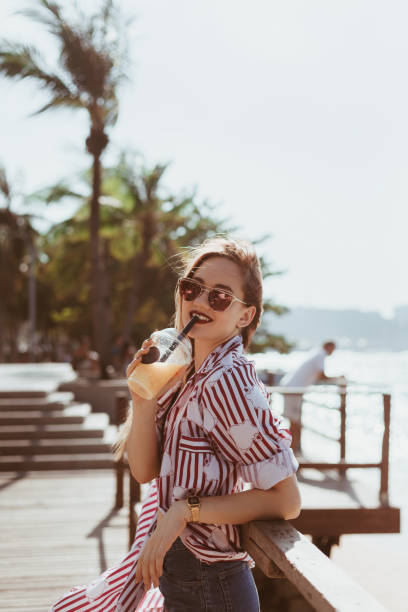 istock smiling young woman drinking cocktail on pier 929555732