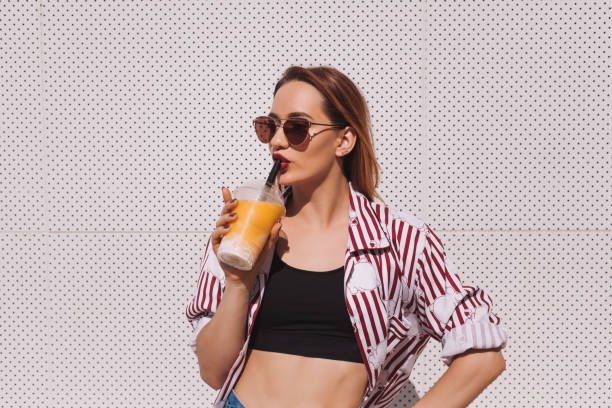 istock beautiful young woman with mango shake in plastic cup 929555900
