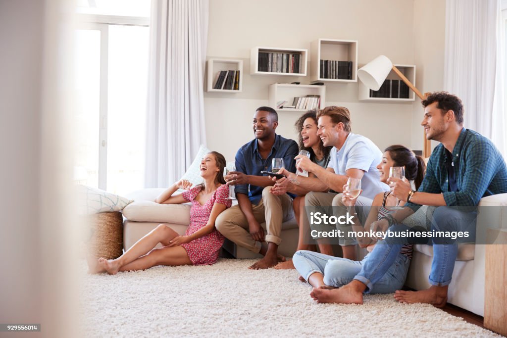 Group Of Friends Relaxing At Home Watching TV Together Wine Stock Photo