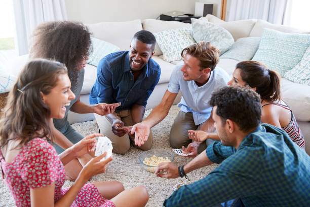 Group Of Friends At Home Playing Cards Together Group Of Friends At Home Playing Cards Together friends playing cards stock pictures, royalty-free photos & images