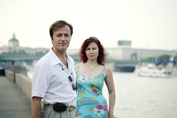 Couple sitting on rocks by the sea, relaxed portrait with soft daylight and copy space—ideal for travel, romance, lifestyle and vacation themes.