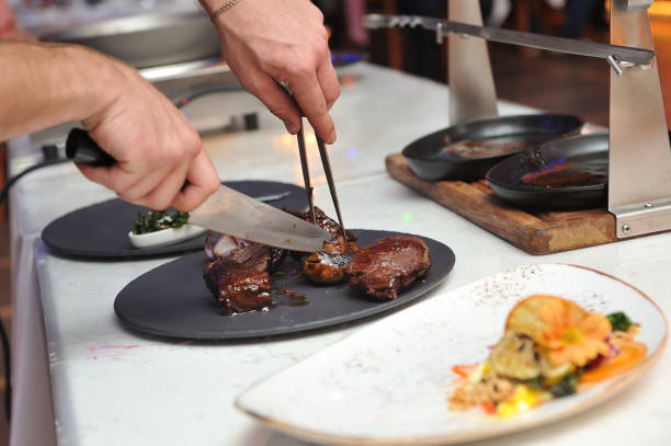 istock Chef, cuts pieces of meat cooked on fire to put it nicely on a plate 929568028