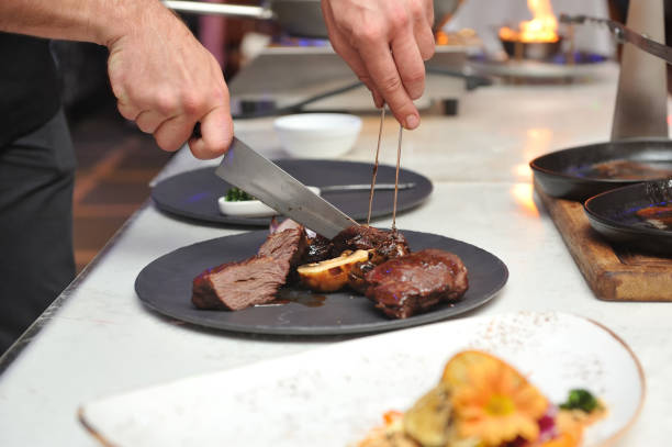 istock Chef, cuts pieces of meat cooked on fire to put it nicely on a plate 929568050