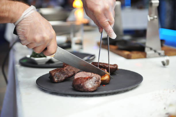 istock Chef, cuts pieces of meat cooked on fire to put it nicely on a plate 929568116