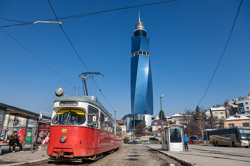 Picture of the Avaz Twist Tower of Sarajevo, the highest skyscraper of former Yugoslavia, with a Sarajevo tram in front, taken on the train station square.