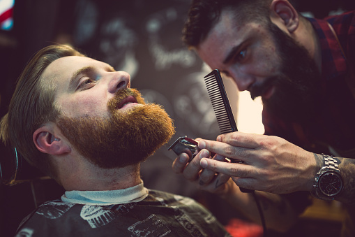 Ginger, bearded guy at the barber shop. Ginger, bearded guy at the barber shop. Barber cutting a beard