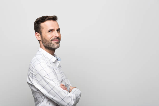 istock Side view of handsome businessman smiling at camera, grey background 929594970