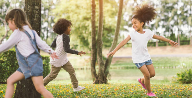 little girl playing with friend - enjoyment spring park small imagens e fotografias de stock