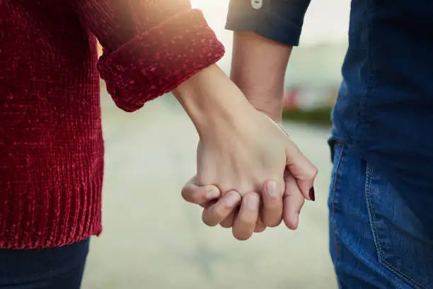 Cropped shot of a couple holding hands outdoors