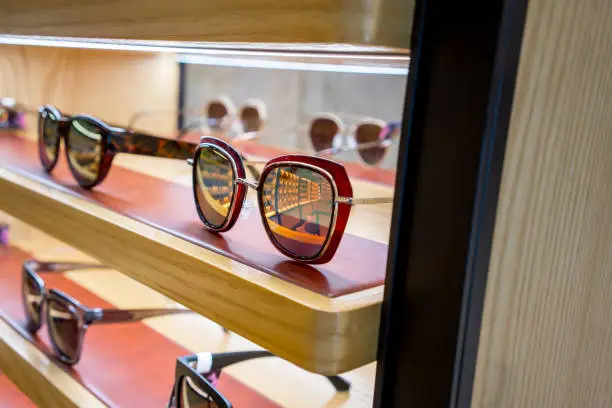 Photo of Various of colorful sun glasses in the shop display shelves. Selective focus