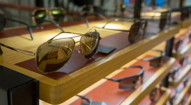 Photo of Various of colorful sun glasses in the shop display shelves. Selective focus