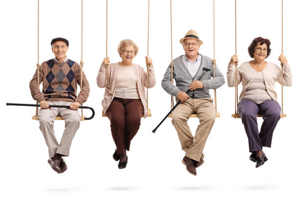 Cheerful seniors sitting on wooden swings and looking at the camera Cheerful seniors sitting on wooden swings and looking at the camera isolated on white background happiness four people cheerful senior adult stock pictures, royalty-free photos & images