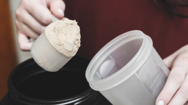 va a verter polvo de proteína de caseína en la taza. - protein concentrate fotografías e imágenes de stock