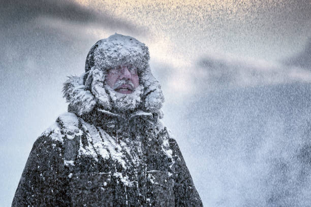 winterliche szene eines mannes mit pelzigen und vollbart zitternd in einem schneesturm - kälte stock-fotos und bilder
