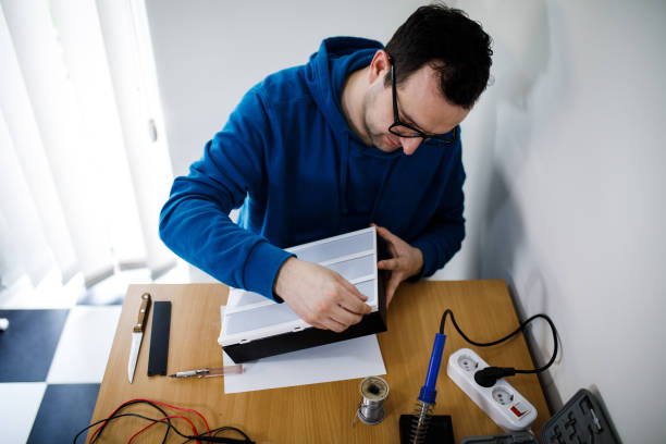 istock Young man tech or engineer repairs electronic equipment, home work on the table. 929661846