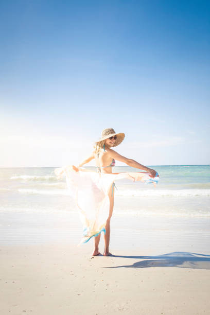 istock Woman With Textile Wearing Hat While Standing At Beach Against Clear Sky During Sunny Day 929665932