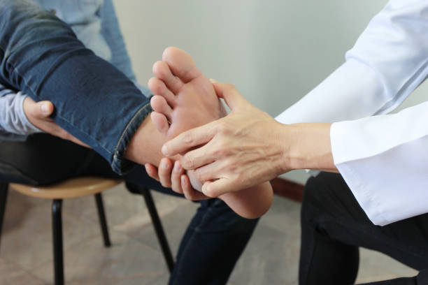 primo piano dell'uomo che sente dolore al piede e medico il traumatologo esamina o trattamento su sfondo bianco, concetto sano - on foot foto e immagini stock