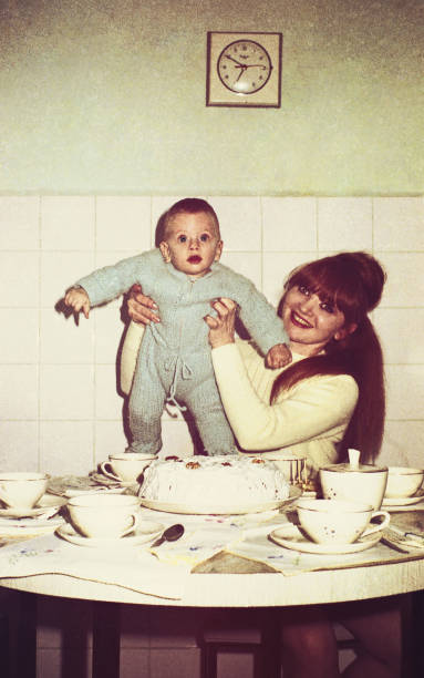 Vintage mommy and baby in the kitchen vintage colored image of a mother holding her baby boy in the kitchen. baby boys photos stock pictures, royalty-free photos & images
