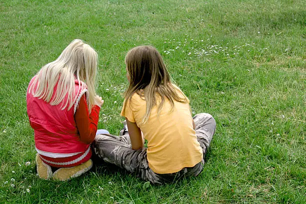 Photo of Best friends - two girls  picking daisies from the lawn