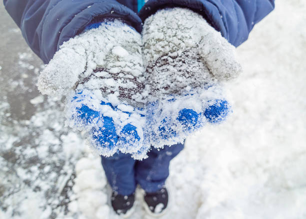 istock A child in knitted gloves in the snow. Cropped image, selective focus. 929701798