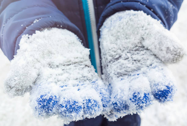 istock A child in knitted gloves in the snow. Cropped image, selective focus. 929701824