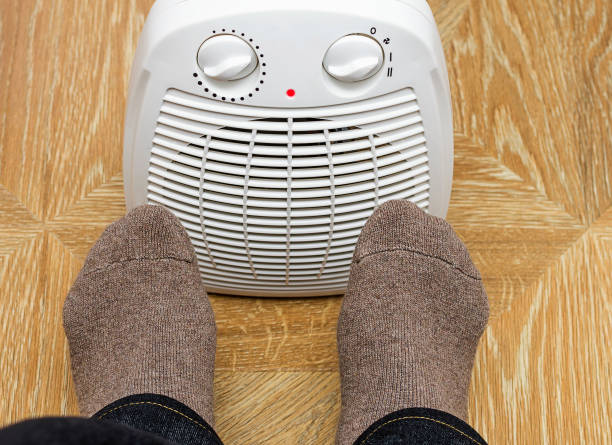 istock Man warming feet by front electric heater. 929701974