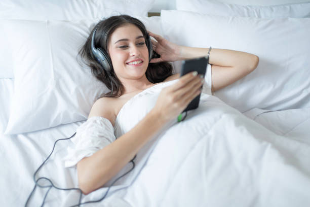 istock Charming woman on bed wearing headphone enjoy music on weekend 929704868