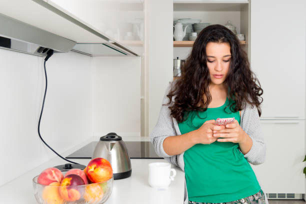 istock Young woman using a mobile phone while having a cup of tea 929719290