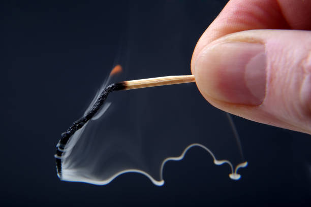 istock Burning and smoking wooden match in hand on dark background 929731786