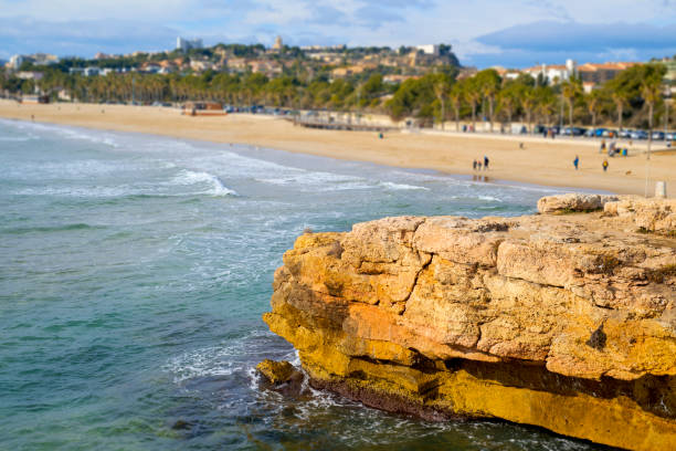a view of the Arrabassada Beach in Tarragona, Spain, and its promenade on a winter day, with the old town of the city in the background, highlighting the dome of the Cathedral