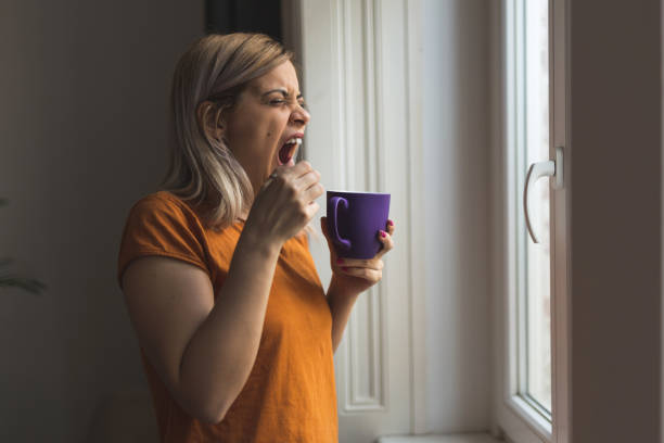 signora che cerca di svegliarsi con il caffè - yawning women drink coffee cup foto e immagini stock