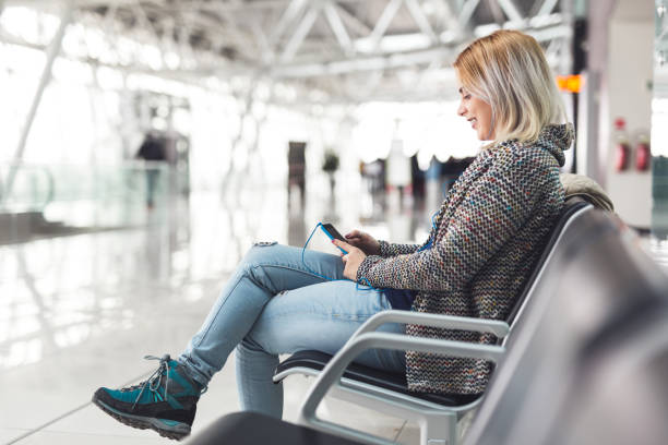 mujer feliz en el aeropuerto con smartphone - airport waiting room waiting airport lounge fotografías e imágenes de stock