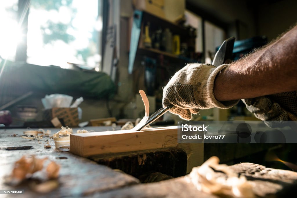 An experienced carpenter shapes wood with a chisel An experienced carpenter shapes wood with a chisel. Carpenter Stock Photo