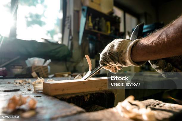 An Experienced Carpenter Shapes Wood With A Chisel Stock Photo - Download Image Now - Carpenter, Carving - Craft Activity, Wood - Material