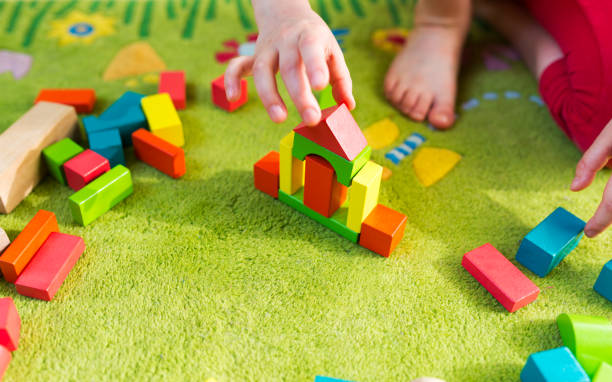 istock Small child playing with wooden blocks on green carpet 929756374