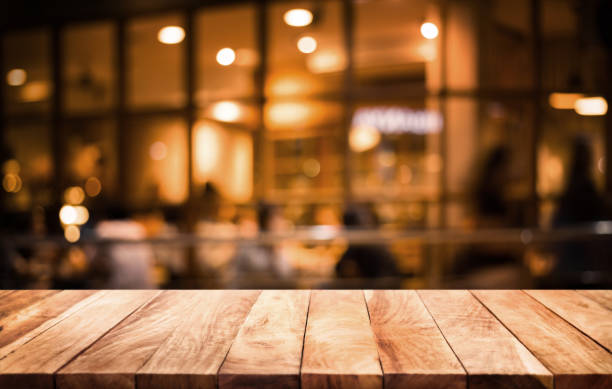 Wood table top on blurred of cafe ( restaurant ) with light gold in dark nigh background.For montage product display or key visual layout. Wood table top on blurred of cafe ( restaurant ) with light gold in dark nigh background.For montage product display or design key visual layout. food court photos stock pictures, royalty-free photos & images