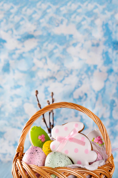 istock Easter cookies, bunnies and Multicolored Easter eggs in a basket on light blue background 929761486