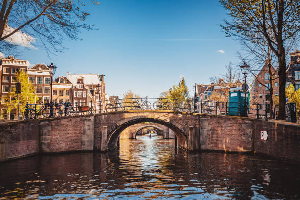 amsterdam-stadsgezicht met kanaal en bruggen in nederland - grachtenpand stockfoto's en -beelden