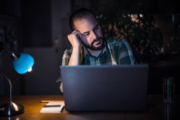 istock Tired man using laptop and working late from home 929769276