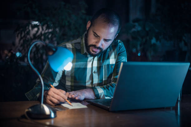 istock Handsome man working late and using laptop in the home office 929769456