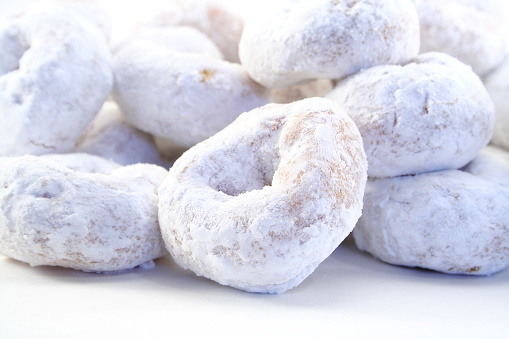 Pile of mini powdered sugar donuts against a white background