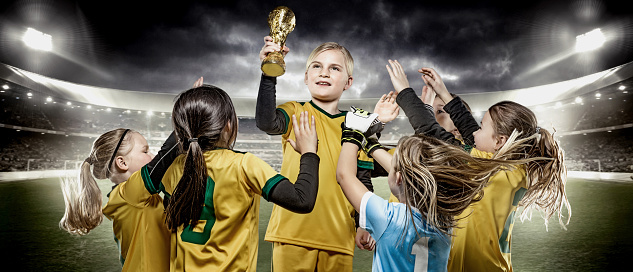 Girls football team celebrating with soccer trophy